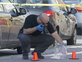 A police officer photographs evidence at Carillon Park near the scene of a stabbing on Montreal Road in Ottawa on Thursday, April 27, 2017.