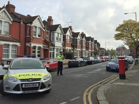 Police officers man the cordoned off area in London's Harlesden Road Friday, April 28, 2017, after British counter-terror police have shot a woman and arrested several people in raids in London and southeastern England. The injured suspect has been hospitalized in serious condition after the raid in northwest London. (Harriet Line/PA via AP)