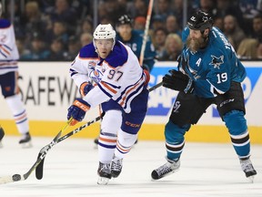 Connor McDavid of the Edmonton Oilers, left, controls the puck in front of Joe Thornton of the San Jose Sharks on his way to scoring an empty net goal at the end of the third period of Game 6 of the Western Conference First Round during the 2017 NHL Stanley Cup Playoffs at SAP Center on April 22, 2017 in San Jose, California. Thornton played the series on torn knee ligaments.