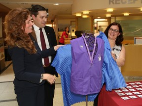 Kathleen Woodard, left, CIBC senior vice-president and region head of Ontario, Alex Baboulas, general manager of the CIBC branch at the New Sudbury Centre, and Angela Corsi-Raso, volunteer advisor at the Northeast Cancer Centre, unveil new volunteer vests during a CIBC donation announcement at the cancer centre in Sudbury, Ont. on Friday April 28, 2017. The $200,000 donation to the Northern Cancer Foundation will go to developing the volunteer program at the cancer centre. The money will be used to improve volunteer visibility with new NCF and CIBC branded vests, food and drink vouchers for volunteers during their breaks, and for any training needed by the volunteers. John Lappa/Sudbury Star/Postmedia Network