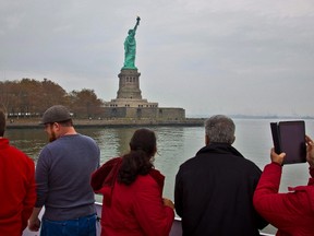 Visitors view the Statue of Liberty during a ferry ride to Liberty Island in New York on Nov. 5, 2015. New York's tourism industry is worried U.S. President Donald Trump's "America First" policies are turning off Canadian visitors, and they're heading north this week to woo Canucks and their tourism dollars. The head of New York City's official tourism organization, NYC & Company, minces no words in admitting he's keen "to counter a little bit of the negative rhetoric that is coming out of Washington." THE CANADIAN PRESS/AP, Bebeto Matthews