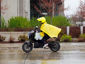Luke Hendry/The Intelligencer
A rain-suited rider of an electric bicycle zips along a very wet Bridge Street West outside the Quinte courthouse Tuesday. Heavy rainfall has caused flooding around the city and region.