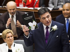 Ontario Finance Minister Charles Sousa reads the budget at Queen's Park as Premier Kathleen Wynne listens on April 27, 2017. (THE CANADIAN PRESS)