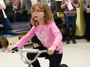 Abby Curzon rides her bike at the cheque presentation from the Fund-racers walk/run fundraising effort for KidsInclusive. The $30,795 raised will go towards helping families with the cost of mobility equipment and related items for disabled youth and children in Kingston. (Gracie Postma/For The Whig-Standard)