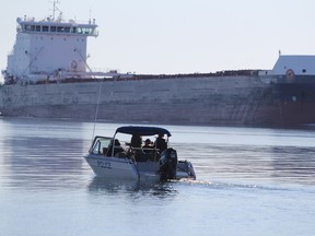 Algoma Central freighter Equinox passes by police boat assisting in search for missing snowmobiler John Szczepanik, 45, of Sault Ste. Marie, on St. Mary's River in Sault Ste. Marie, Ont., on Wednesday, May 3, 2017. (BRIAN KELLY/THE SAULT STAR/POSTMEDIA NETWORK)