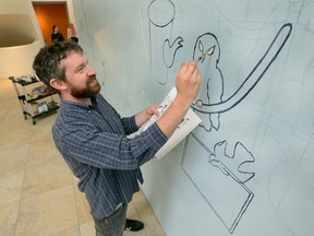 Artist Billy Bert Young starts work on a mural on the construction cladding that will stand while Museum London?s new Centre at the Forks is under construction. (MORRIS LAMONT, The London Free Press)