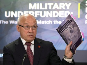 Senator Daniel Lang holds up a copy of the Defence Policy Report during news conference in Ottawa, Thursday April 13, 2017. (THE CANADIAN PRESS/Adrian Wyld)