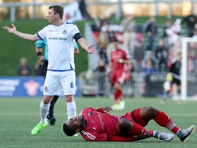 Edmonton FC captain Nick Ledgerwood tries to explain lack of fault to the ref as Ottawa FC's Eddie Edward writhes in pain after they tangled on the field in the first leg of the Canadian Championship at TD Place in Ottawa on Wednesday, May 3, 2017. (Julie Oliver)