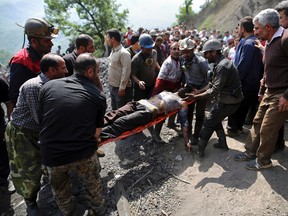 In this picture released by the Tasnim News Agency, miners and rescue personnel carry an injured mine worker after a coal mine explosion, near Azadshahr in northern Iran, Wednesday, May, 3, 2017. Iranian state media said Wednesday that a large explosion struck the coal mine, trapping dozens of miners and killing at least two. Ambulances, helicopters and other rescue vehicles raced to the scene on Wednesday in Golestan province as authorities worked to determine the scale of the emergency. (AP Photo/Tasnim News Agency, Mostafa Hassanzadeh)