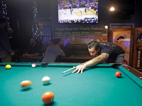 In this Tuesday, May 2, 2017 photo, Dustin Smith, 28, plays pool as the Utah Jazz-Golden State Warriors NBA basketball playoff game is broadcast on a television at Poplar Street Pub in Salt Lake City. Salt Lake City leaders and tourism officials playfully jabbed back at Golden State Warriors players who bemoaned the lack of nightlife in Utah, hoping to combat the predominantly Mormon state's reputation as a boring place where it's tough to get a drink. The tourism agency in the state capital launched a new website and video Monday titled, "There's nothing to do in Salt Lake" that features people enjoying drinks and food at popular breweries, bars, restaurants and sporting venues. (AP Photo/Rick Bowmer)