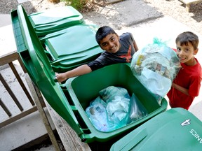 Eight-year-old Montessori Academy of London students Sagar Parekh (left) and William Sartori toss a bag of organic waste into a green bin at their school. After implementing a green bin program at the end of March, Montessori Academy officials estimate that the school has reduced the amount of trash it sends to the landfill by 80-85 per cent CHRIS MONTANINI\LONDONER\POSTMEDIA NETWORK