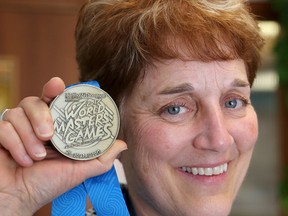 Diana Drury holds her gold medal from the World Masters Games in her office at Queen's University on Wednesday. (Ian MacAlpine/The Whig-Standard)