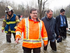 Montreal Mayor Denis Coderre walks through the flooded streets of the Ile-Mercier district of Ile-Bizard, Que., on Friday, May 5, 2017. Forecasts are calling for several more days of rain. THE CANADIAN PRESS/Ryan Remiorz