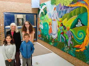 Artist Maureen Walton poses for a photo with students Madison Pople, front left, Noah Douglas and Avery Marcella in front of the Mother Teresa Catholic School's new mural in honour of the school's namesake, Saint Teresa of Calcutta, painted with the help of the students. (Julia McKay/The Whig-Standard)