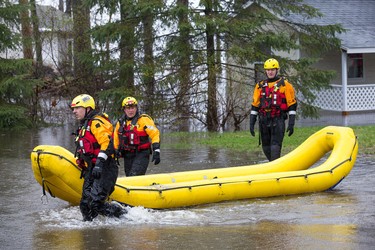 Firefighters check on a resident as the residents of Constance Bay deal with the Ottawa River rising to record levels and  flooding the region.  Wayne Cuddington/Postmedia