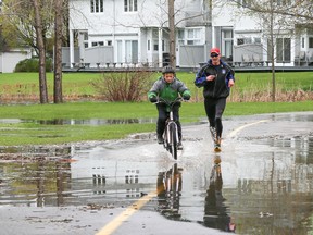A pair of residents splash through a flooded out section of the Waterfront Trail on Saturday May 6, 2017 in Belleville, Ont. On Saturday Quinte Conservation issued a flood warning for the region. Tim Miller/Belleville Intelligencer/Postmedia Network