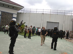 Police officers armed with tear gas launchers stand guard outside Sialang Bungkuk Prison following the escape of hundreds of its inmates in Pekanbaru, Riau province, Indonesia, Friday, May 5, 2017. Indonesian authorities are searching for scores of inmates who escaped Friday from the overcrowded prison on Sumatra island. (AP Photo)
