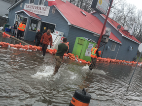 Volunteers pile orange sandbags around the Lighthouse Grocery and Restaurant on Bayview Drive, a community hub for generations in Constance Bay. KELLY EGAN / POSTMEDIA