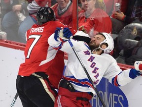 Senators centre Kyle Turris hits New York Rangers winger Tanner Glass against the boards during Game 5 on Saturday. (THE CANADIAN PRESS)