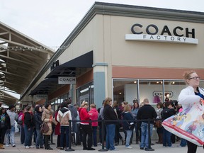 In this Friday, Nov. 27, 2015, file photo, shoppers wait in line outside a Coach factory outlet store at the Cincinnati Premium Outlets, in Monroe, Ohio. Coach is buying rival luxury handbag, clothing and accessories company Kate Spade in a deal valued at $2.4 billion as it looks grab more millennial shoppers, announced Monday, May 8, 2017. (AP Photo/John Minchillo, File)
