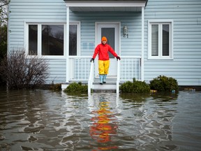 A woman stands on the step of a home at the corner of Rue Blais and Rue Adelard where the heavy flooding has hit in the Gatineau area Sunday May 7, 2017.   Ashley Fraser/Postmedia