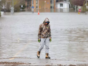 A local resident seems lost in thought after surveying a flooded Rue Saint-Louis in Gatineau as flooding continues throughout the region in areas along the local rivers. WAYNE CUDDINGTON / POSTMEDIA