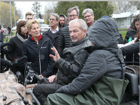 Kathleen Wynne and Jim Watson talk Michel and Maggie Bourbonnais on Morin rd in Cumberland with the flooded Ottawa river in the background, May 08, 2017. The Bourbonnais' house has been flooded.  (Jean Levac, Postmedia)