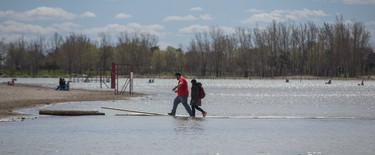 Aaron Acord and his girlfriend Chayanisa Puttamata use a path to cross a flooded Woodbine Beach in Toronto, Ont. on Monday May 8, 2017. (Ernest Doroszuk/Toronto Sun)