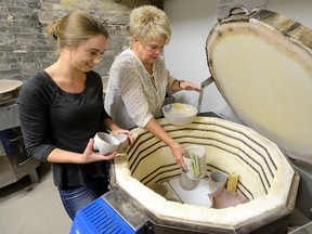 Brenda Duncan, right, and Zara Gardner load a kiln with work at the London Clay Art Centre. (MORRIS LAMONT, The London Free Press)