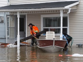 A man helps move wood on the front porch of a home being affected by flood waters in Gatineau, Que.