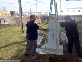 Royal Canadian Legion Branch 44 Whitecourt president Kyle Scott (right) helps lower a new tombstone into the gravesite of a First World War Veteran. Scott applied two years ago to the federal government to have four tombstones at Whitecourt Cemetery replaced, which Veterans Affairs does free of charge (Jeremy Appel | Whitecourt Star).