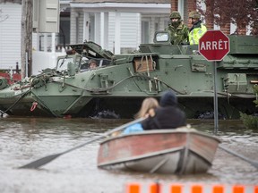 Soldiers in an armoured vehicle drive past a row boat on Rue Glaude in Gatineau.
