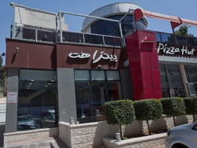 A woman walks by a Palestinian branch of the Pizza Hut company, in the West Bank city of Ramallah, Wednesday, May 10, 2017. (AP Photo/Nasser Nasser)