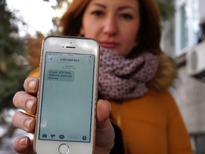 In this photo taken Wednesday, Feb. 22, 2017, television journalist Julia Kirienko holds up her smartphone to show a text message reading “Ukrainian soldiers, they’ll find your bodies when the snow melts”, in Kiev, Ukraine. Ukrainian soldiers fighting pro-Russian separatists are being bombarded by threats and disinformation via text message, the 21st-century equivalent of dropping leaflets on the battlefield. (AP Photo/Raphael Satter)