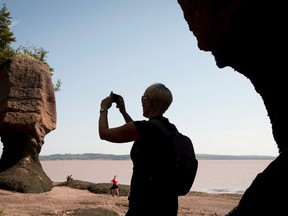 A tourist stops to take a photo of the Hopewell Rocks on the Bay of Fundy, N.B., Friday, August, 16, 2013. New Brunswick had to give Ottawa a geography lesson, Twitter-style, after a federal agency mistakenly put the famous Hopewell Rocks in Nova Scotia. THE CANADIAN PRESS/Jonathan Hayward