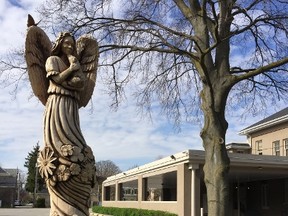 Artist Mike Winia?s angel, carved with a chainsaw out of a large silver maple tree that was destroyed after a storm, stands in front of Needham Funeral Service on Dundas Street