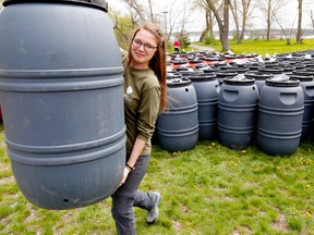 Luke Hendry/The Intelligencer
Quinte Conservation student Tyla Reed of Ameliasburgh hefts a rain barrel, one of 411 recycled food containers sold Friday at Potter's Creek Conservation Area in Quinte West. Last year — the sale's first — just 160 were sold. Spokeswoman Jennifer May-Anderson said last year's drought appeared to have boosted sales. Details will be posted at quinteconservation.ca and on social media If leftover barrels remain for sale. Visit rainbarrel.ca for details of other local sales.