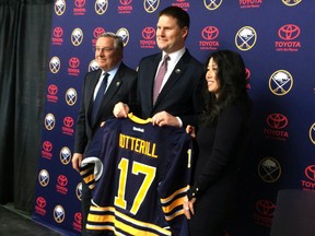 Newly hired Buffalo Sabres' General Manager Jason Botterill, center, displays his Sabres jersey at First Niagara Center in Buffalo, N.Y., Thursday, May 11, 2017. Botterill is leaving the Pittsburgh Penguins to take over a team that owner Terry Pegula, left, criticized for lacking structure and discipline. At right is Kim Pegula, Terry Pegula wife, (AP Photo/John Wawrow)