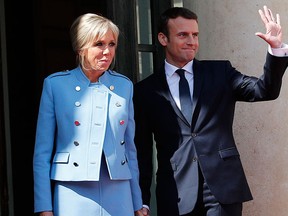Emmanuel Macron waves as he poses for photographers with his wife Brigitte Macron after the handover ceremony with outgoing president Francois Hollande, at the Elysee Palace in Paris, France, Sunday, May 14, 2017. (AP Photo/Christophe Ena)