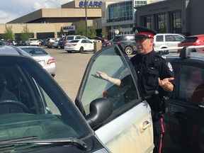 Acting Staff Sgt. Paul Looker with the Edmonton police looks through cars in the parking lot outside of Southgate Centre at 5015 111 St. on May 15, 2017.