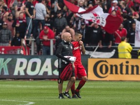 Toronto FC forward Sebastian Giovinco (right) leaves the field with a trainer after suffering a quadriceps strain during his team’s game on Saturday. Giovinco will miss three weeks. (CHRIS YOUNG/The Canadian Press)