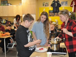 Students Max Miron, left, and Madison Laframboise work alongside Mrs. Chalut to make beeswax lip balm. Photo supplied