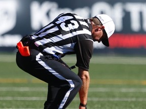 A CFL official picks up a flag off the turf during a game in Calgary on July 18, 2015. (Al Charest/Calgary Sun/Postmedia Network)