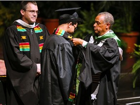In this April 27, 2017 photo, Maurice Cooley, right, Associate Vice President of Intercultural Affairs at Marshall University, presents Demetrius Miller with his Kente cloth during Marshall's spring Donning of the Kente ceremony in Huntington, W. Va. Harvard will join a growing number of universities when it holds its first "Black Commencement" on May 23 to recognize the accomplishments of black students and faculty. (Sholten Singer/The Herald-Dispatch via AP)