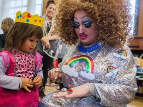 In this Saturday, May 13, 2017 photo, Lil Miss Hot Mess, right, compares outfits with 2-year old Eva McInnes after reading to a group of children during the Feminist Press' presentation of Drag Queen Story Hour at the Park Slope Branch of the Brooklyn Public Library, in New York. (AP Photo/Mary Altaffer)