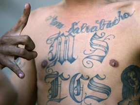 A member of the ‘Mara Salvatrucha’ gang flashes the sign of his gang as he is presented to the press in 2006. (YURI CORTEZ/Getty Images)