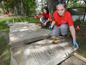 Alyssa Szilagyi, right, and Sunny Kim restore 19th-century headstones Wednesday unearthed at Woodland Cemetery. (MORRIS LAMONT, The London Free Press)