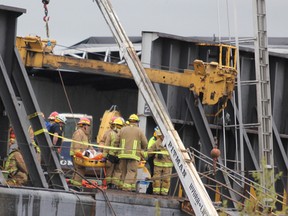Firefighters remove a man from a barge at Purvis Marine on Pim Street late Thursday afternoon.