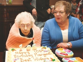 Margaret Bertram blows out the candles on her birthday cake. Her daughter Ethel is sitting beside her
