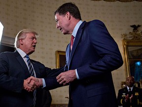 U.S. President Donald Trump (C) shakes hands with then-FBI Director James Comey during an Inaugural Law Enforcement Officers and First Responders Reception in the Blue Room of the White House on Jan. 22, 2017 in Washington, D.C.  (Photo by Andrew Harrer-Pool/Getty Images)